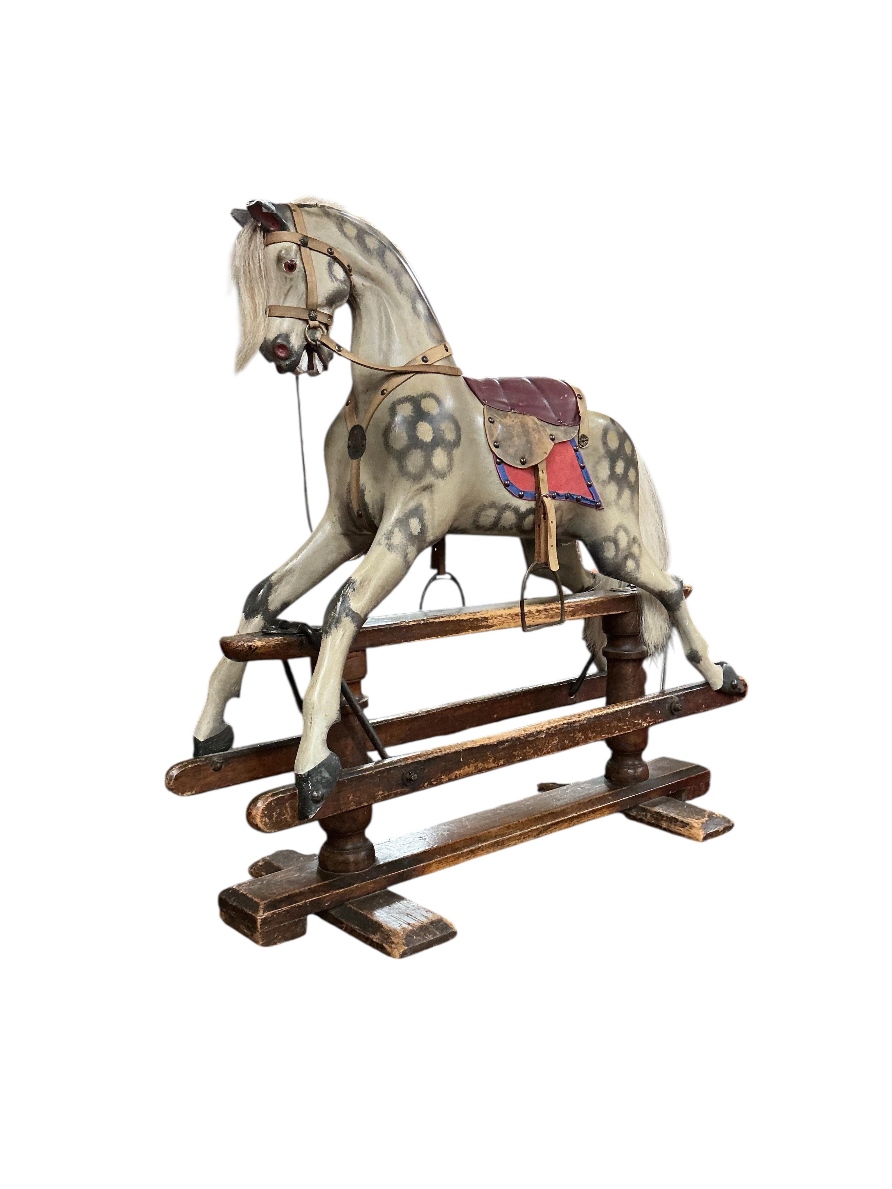 An Ayres type dappled grey painted rocking horse, pine base and runners with good patination and applied brass roundels to both the base and the horse celebrating Queen Victoria‘s Golden Jubilee in 1887, the horse has be